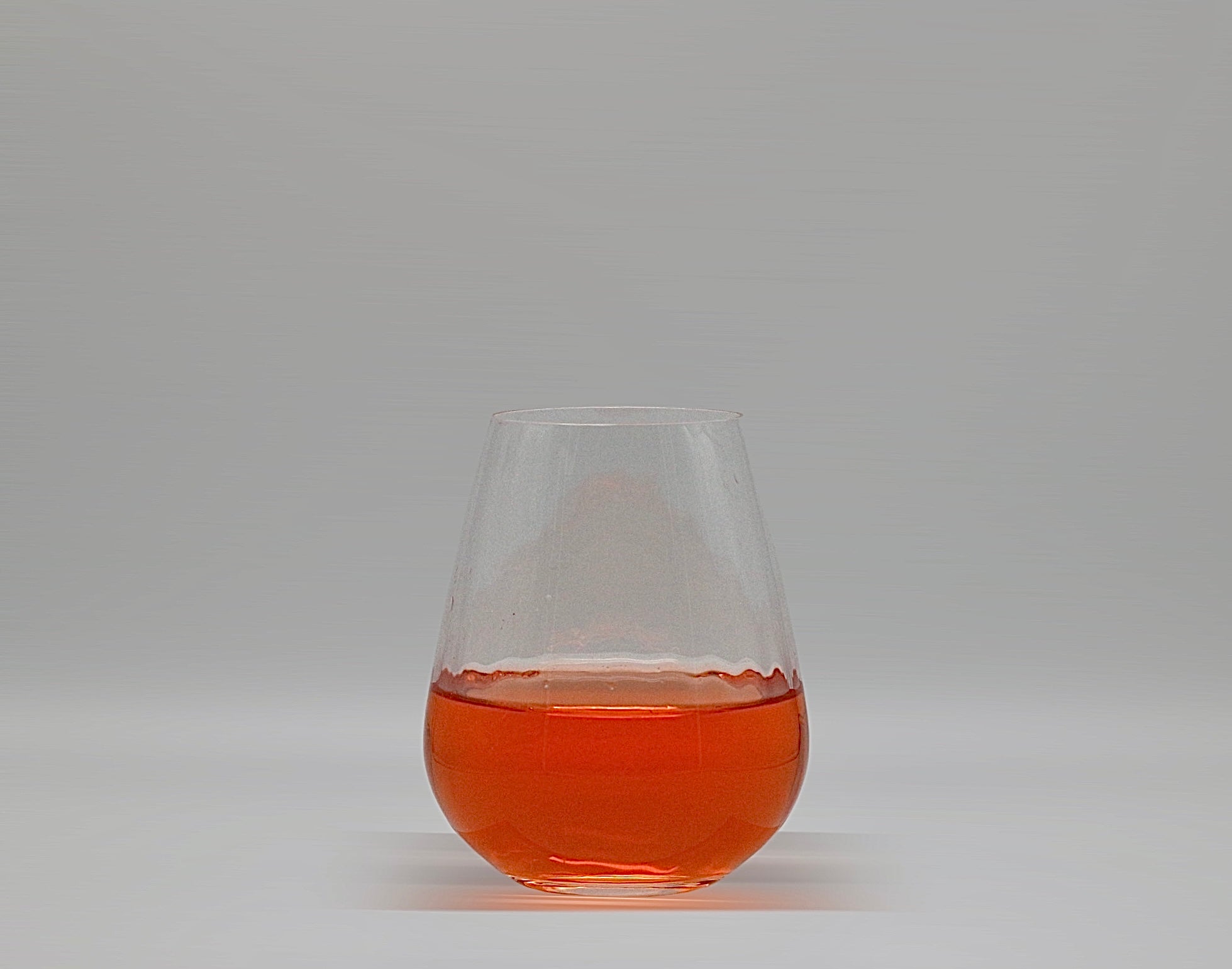 Wasserglas mit gewellter Struktur mit oranger Flüssigkeit.