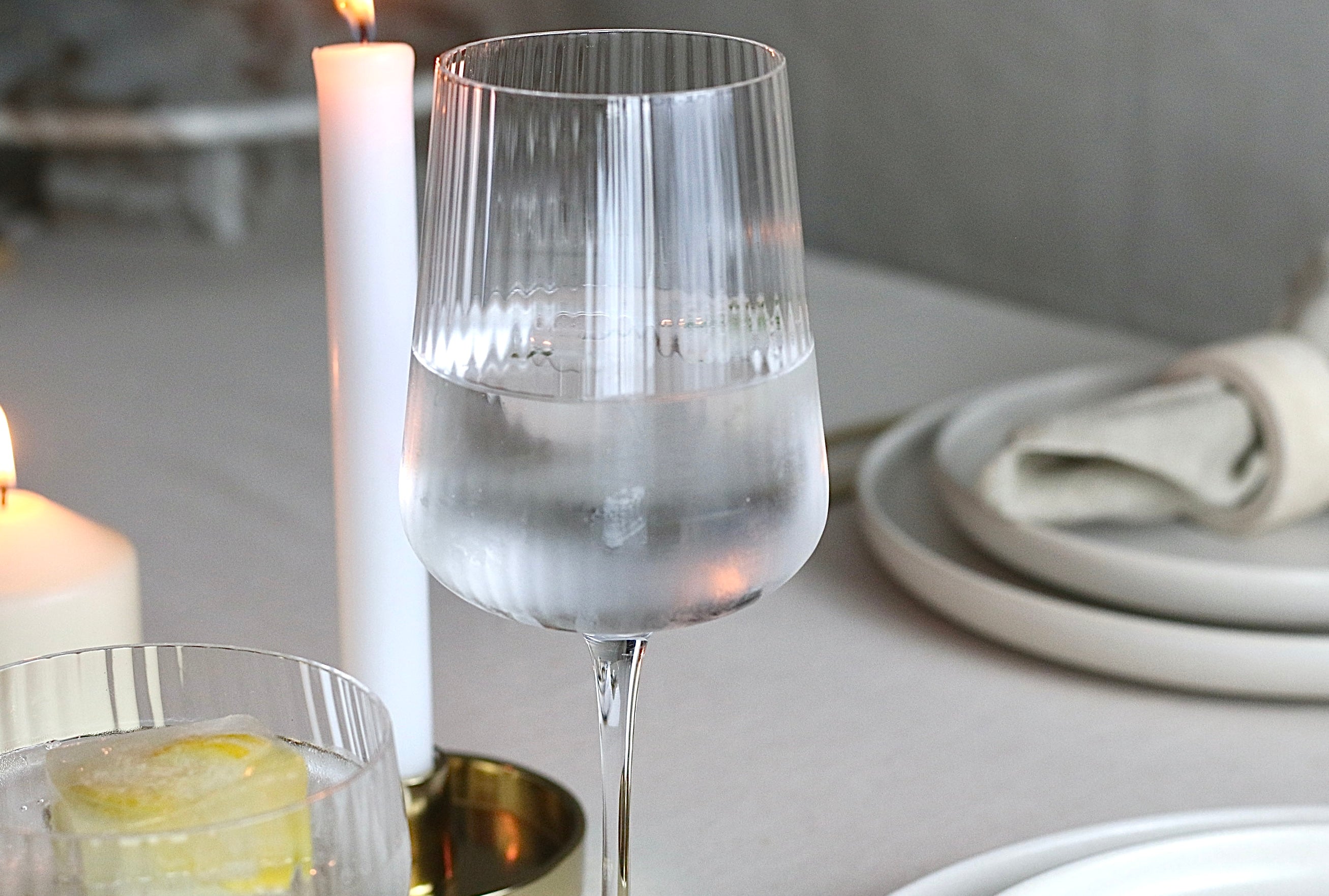 Weinglas mit geriffelter Struktur auf elegant gedecktem Tisch.