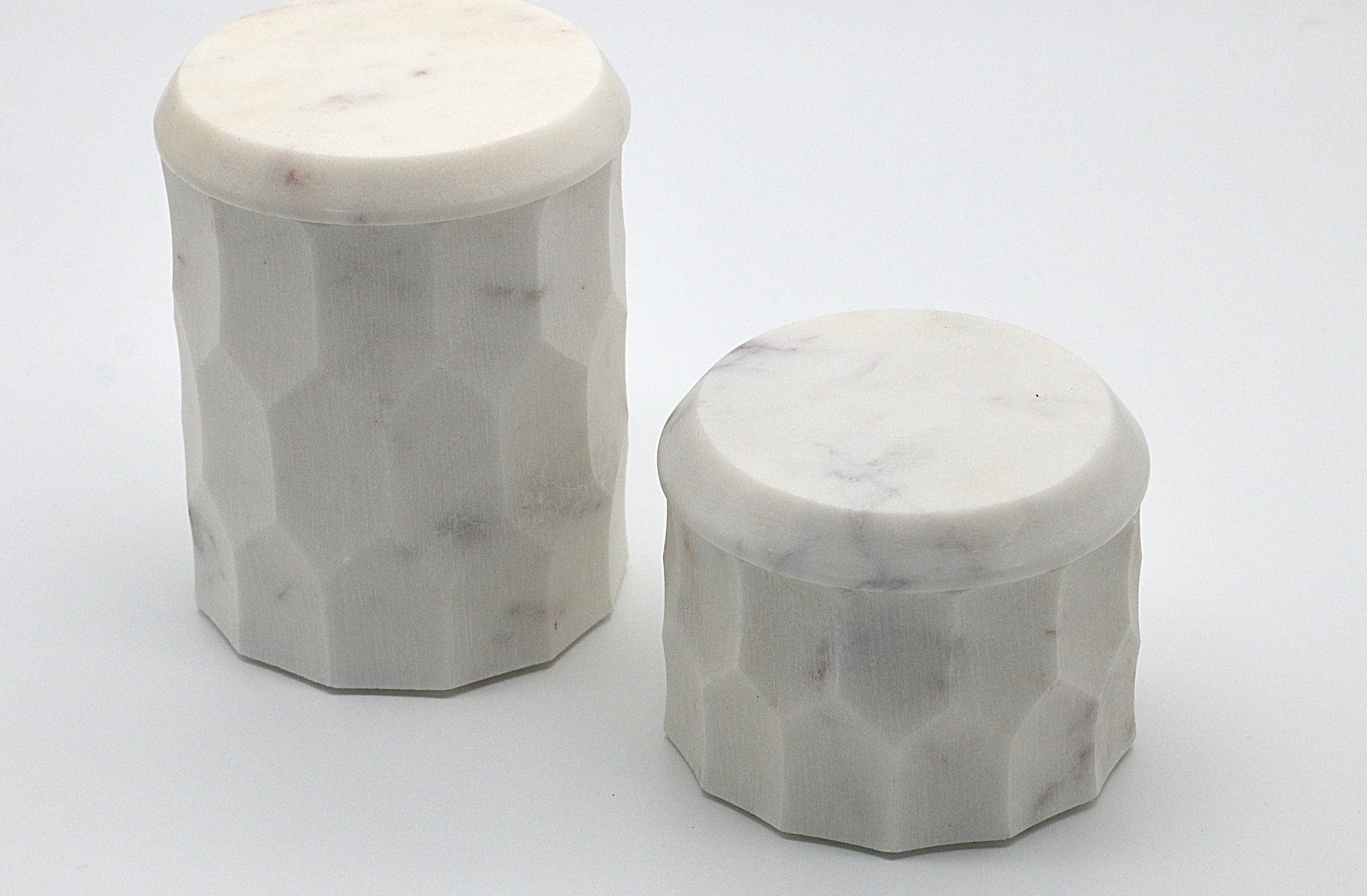 Zwei Aufbewahrungsdosen aus Marmor mit facettierter Oberfläche im modernen Design in weiß.