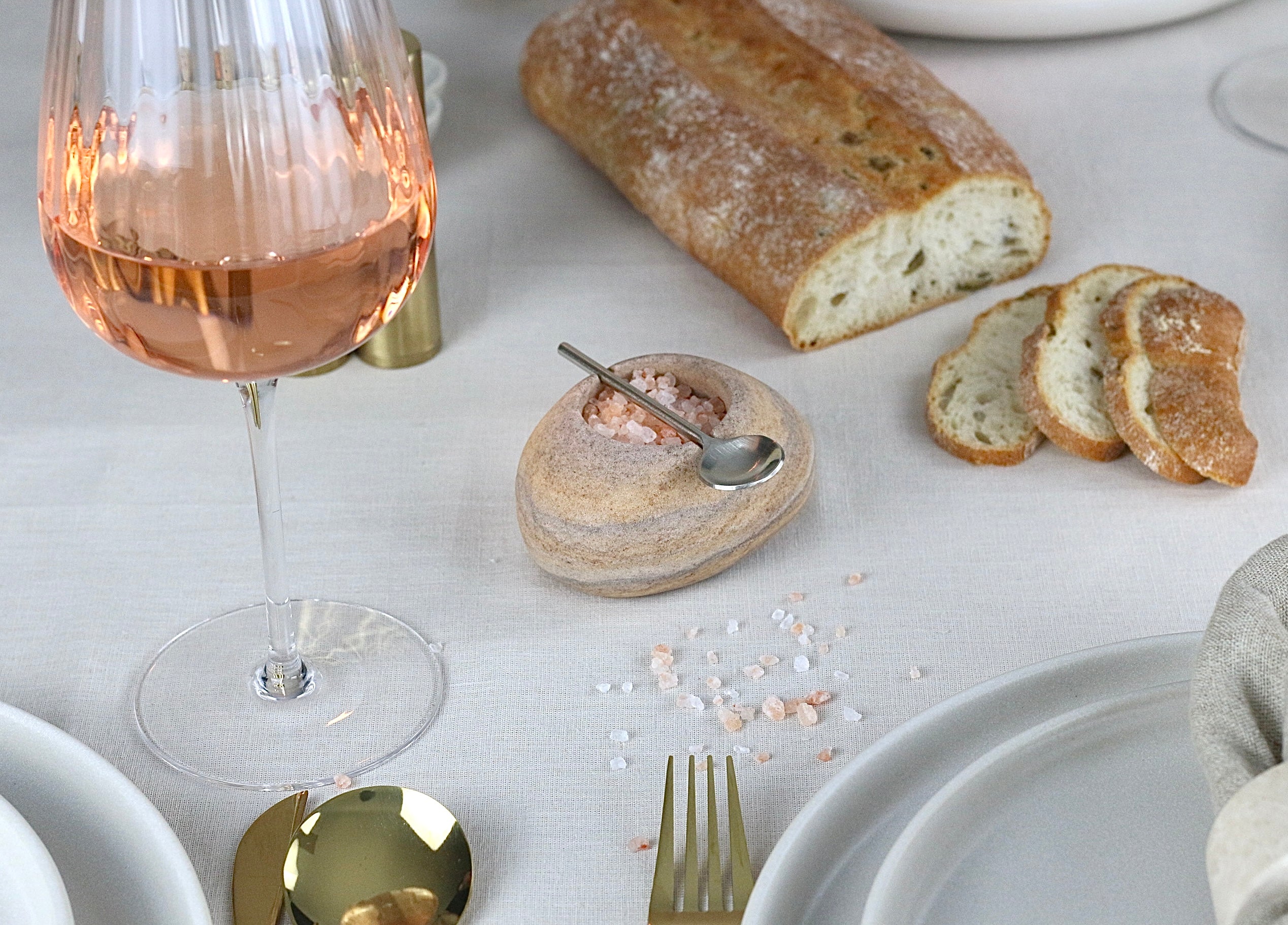 Beige-braun-grau marmorierte Gewürzschale aus Sandstein mit passendem Löffel, auf einem elegant gedeckten Tisch.